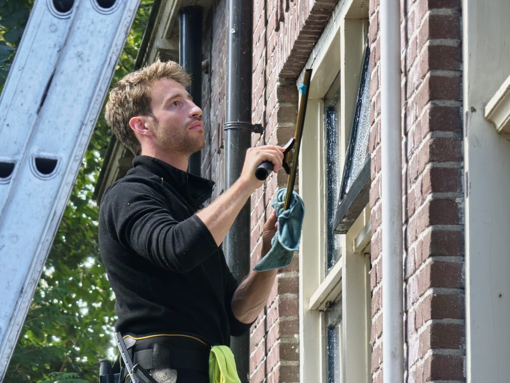 Glazenwasser trekt een raam droog met een wisser