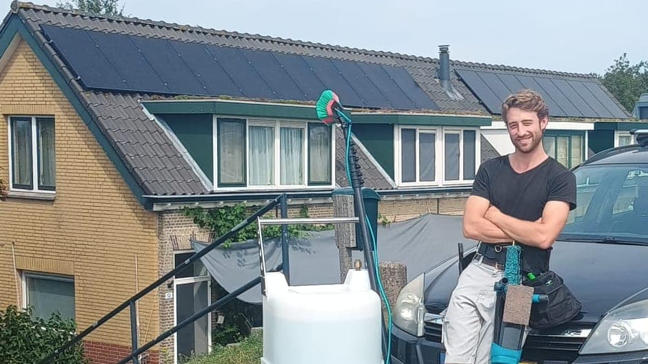 Glazenwasser met osmosetank en telescoopsteel voor een rij huizen met zonnepanelen